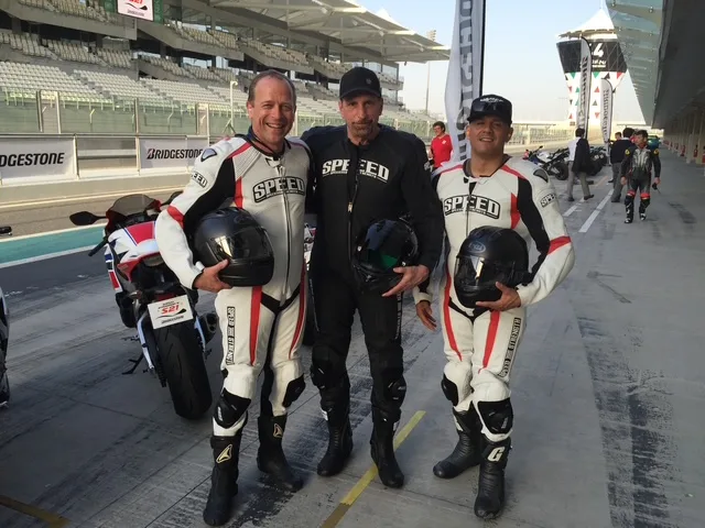 Three riders in race leathers on pit lane