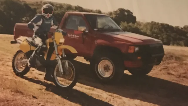 Vintage dirt bike parked beside a pickup truck